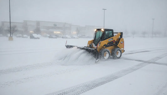 Skid steer loader with heavy-duty snow plow attachment clearing snow on a commercial parking lot
